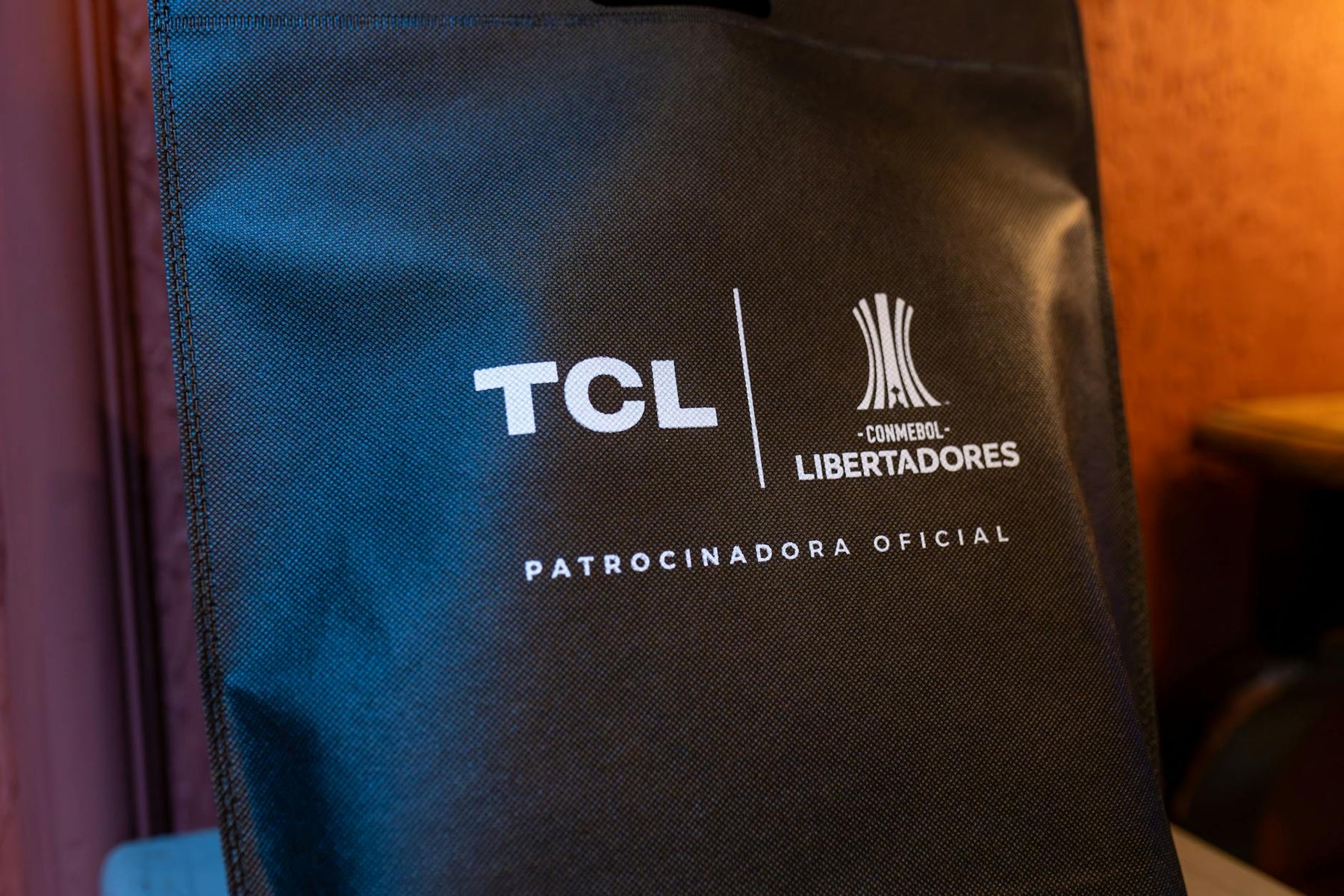 Close-up of a black sponsorship bag showing TCL and CONMEBOL Libertadores logos with brand details.