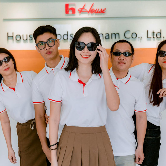 Group of five colleagues wearing polo shirts and sunglasses indoors at company office.