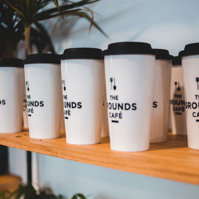 Designed white for coffee with black silicone lids and cutlery symbols on shelf for sale in coffee shop