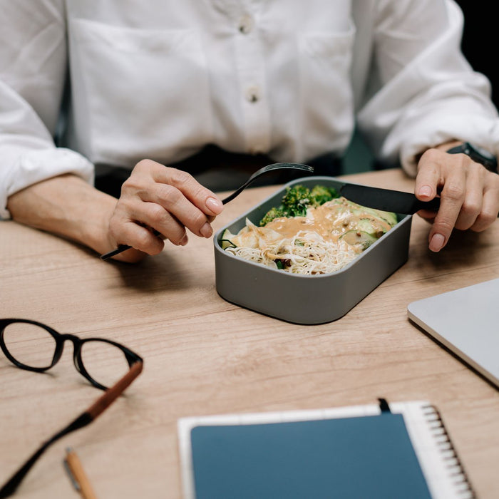 Adult enjoying a healthy meal at the office desk during lunch break.