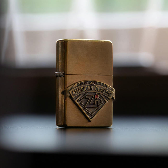 Close-up of a vintage brass Zippo lighter with American Classic logo, captured in soft lighting.