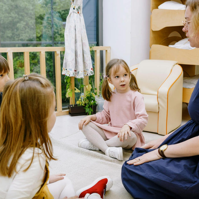 Teacher interacting with children in a cozy, educational setting.