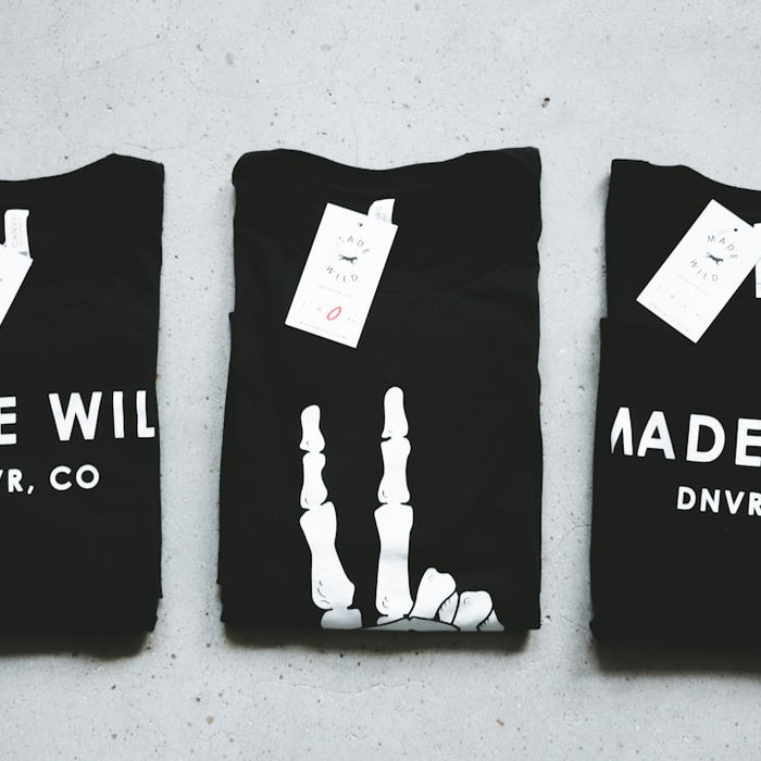 three assorted black crew-neck shirts on gray surface