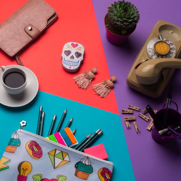 pencils on pouch beside coffee cup with saucer, cup with ballpoin pens near brown telephone, succulent plants, kalavera case, and brown wallet