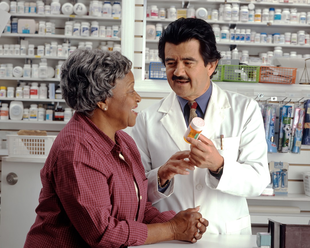A pharmacist in a white coat showing a pill bottle to a woman