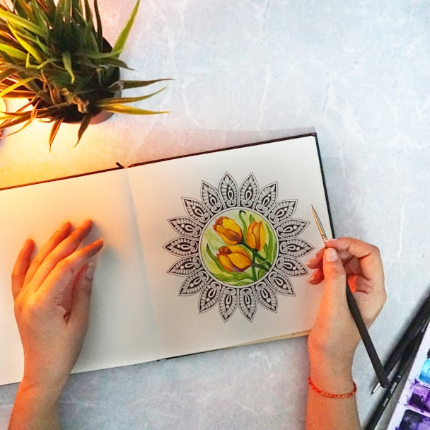 person holding white and green flower painting