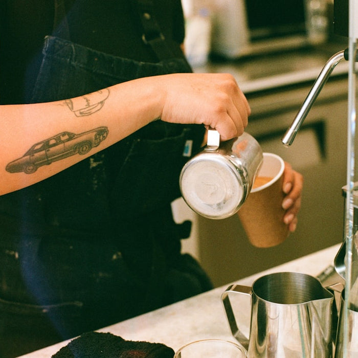 a woman pouring a cup of coffee in a kitchen
