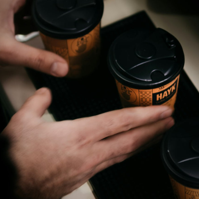 a person holding two cups of coffee on top of a table