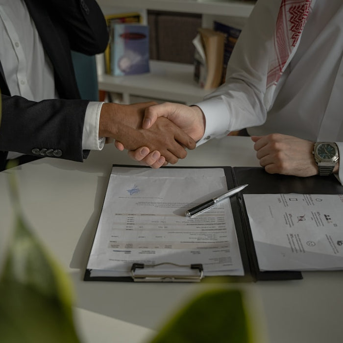 two people shaking hands over a piece of paper