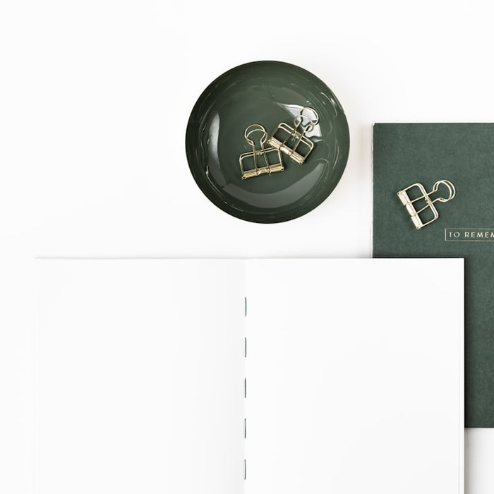 a desk with a clock, notebooks, and papers on it