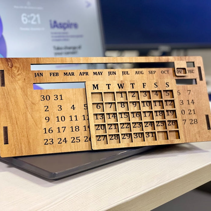 a wooden calendar sitting on top of a laptop computer