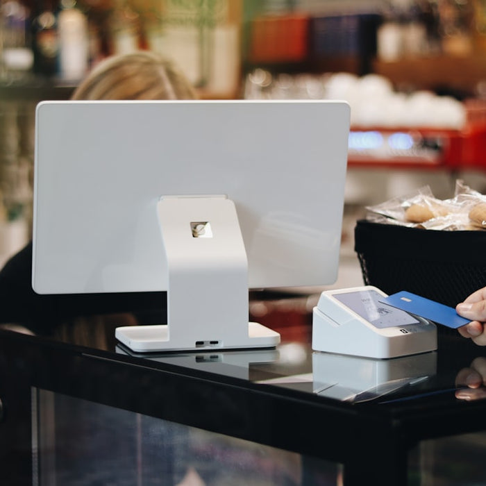 A person holding a credit card in front of a computer