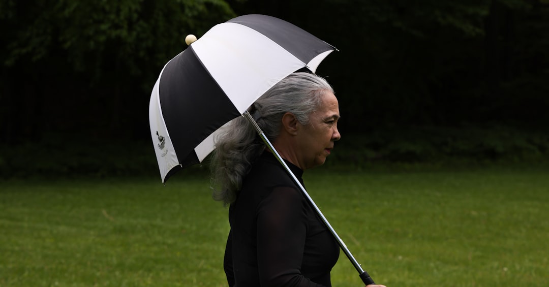 A person walks underneath a black and white umbrella.