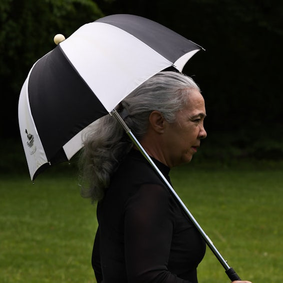 A person walks underneath a black and white umbrella.