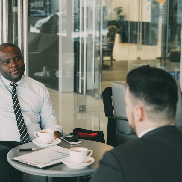 Two businessmen talking at a cafe table.