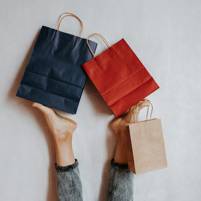 Three shopping bags held by legs on white background