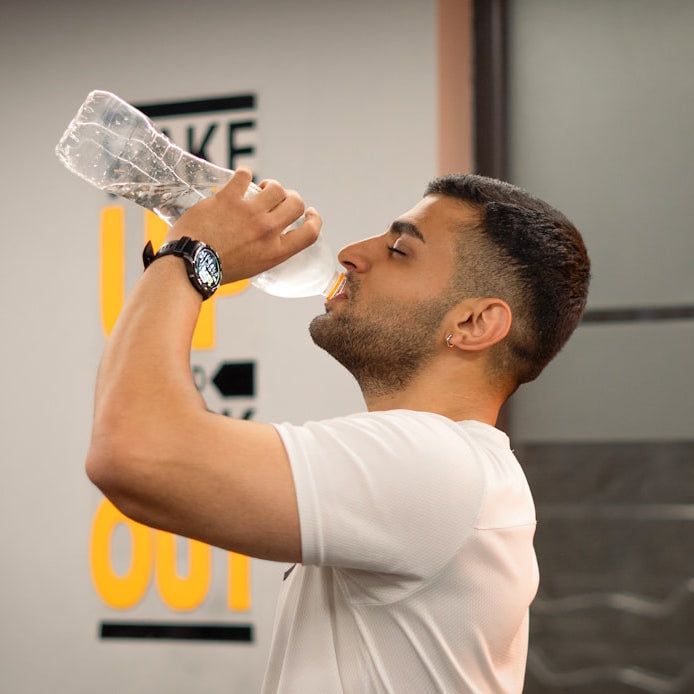 Man drinking water from bottle in gym.