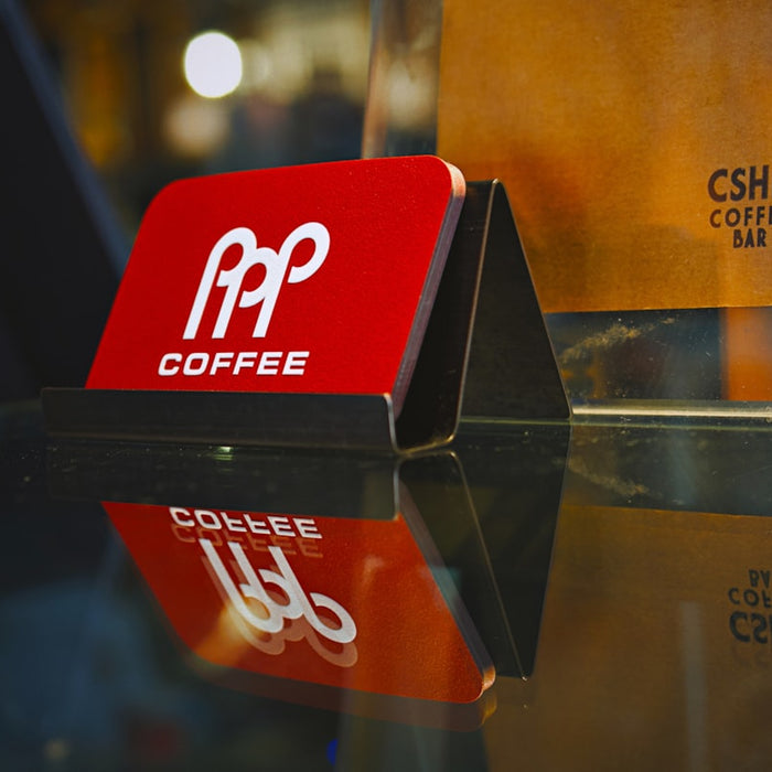 Red coffee sign with logo reflects on glass surface