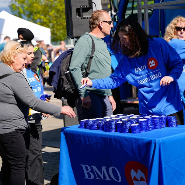 People receiving drinks from a table at an outdoor event.