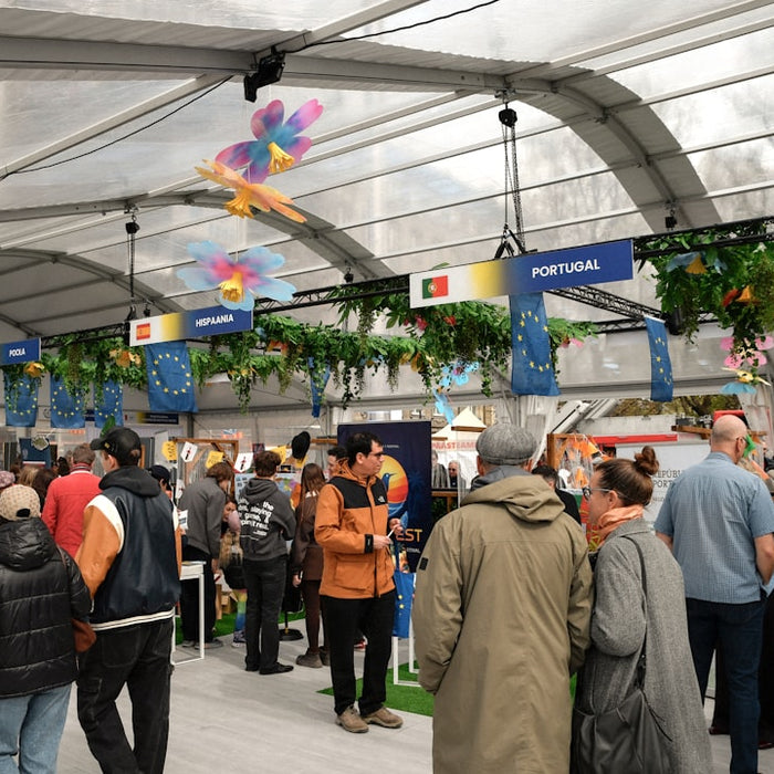 Crowd gathered inside a large tent with decorated stalls.