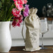 Cotton Wine Drawstring Bag - A cream cotton drawstring bag with a logo, holding a wine bottle, next to a vase of pink flowers and glasses.