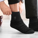 June Business Socks - Black socks being worn, featuring a subtle logo on the side. The person is adjusting them while seated.