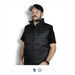 Swiss Peak Urban Puffer Vest - A man wearing a black puffer vest, featuring a zip closure and high collar, with a logo on the chest.