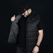 Swiss Peak Urban Puffer Vest - A man in a black Swiss Peak Urban Puffer Vest, holding it open to display the interior lining.