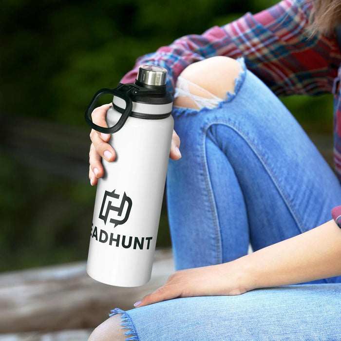 Solana Bottle - A drink bottle in white with a black lid and handle, featuring a logo. The bottle is held by a person in casual attire.