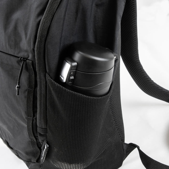 Frontier Trail Daypack - A black daypack features a side mesh pocket holding a black drink bottle. The bag has zippers and adjustable straps.