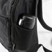 Frontier Trail Daypack - A black daypack features a side mesh pocket holding a black drink bottle. The bag has zippers and adjustable straps.