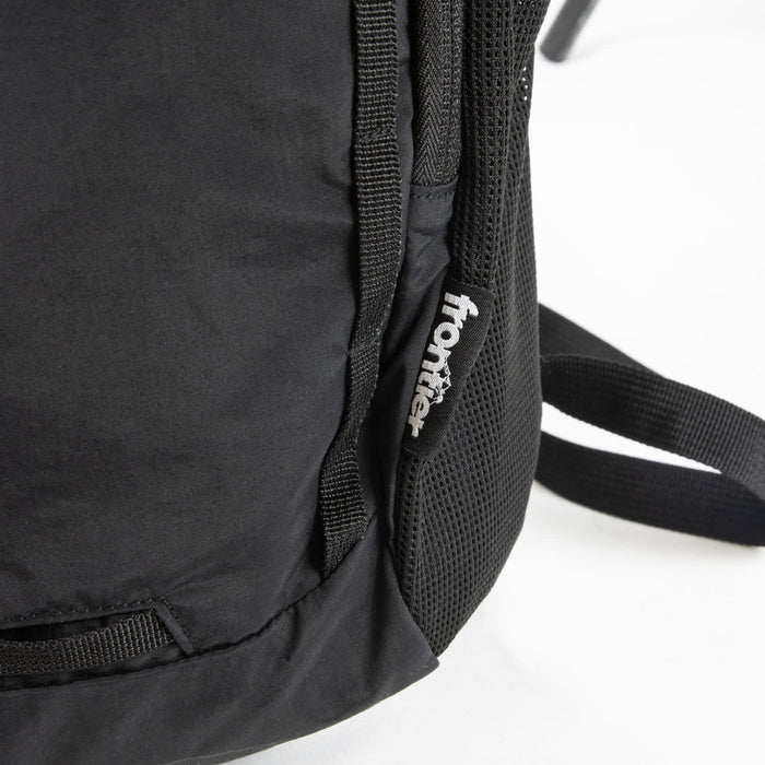Frontier Trail Daypack - A black daypack with mesh detailing and a logo on the side. The straps are partially visible.