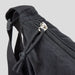 Selene Moon Bag - A black bag featuring a zip closure and adjustable strap, with a woven texture. It includes a logo on the side.