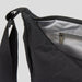 Selene Moon Bag - A black bag with a zippered opening and an interior pocket, featuring a sturdy strap. It has a simple, sleek design.