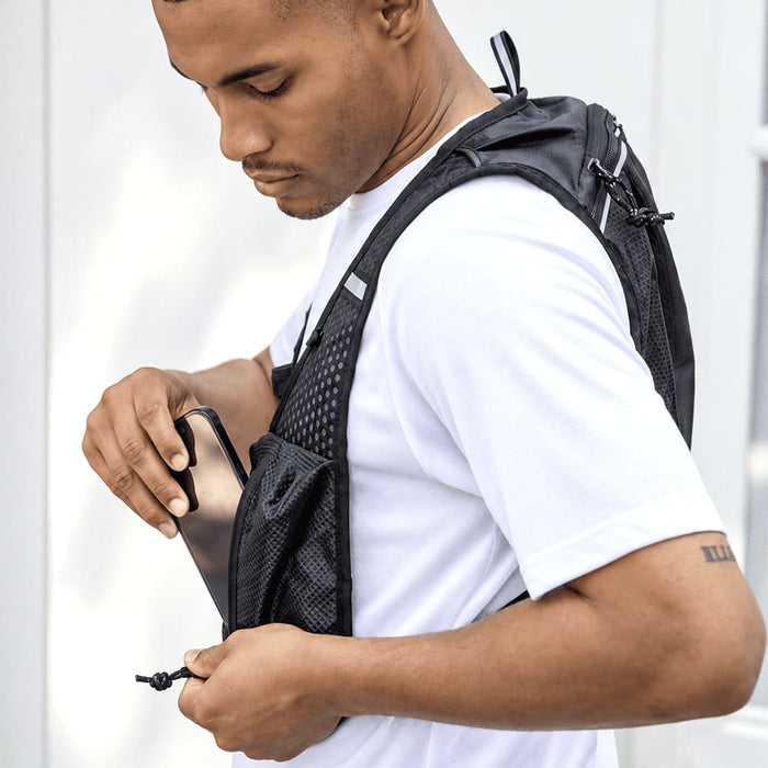 Varyon GRS Recycled Running Vest Hydration Pack 5L - A black recycled running vest hydration pack being worn by a man, featuring mesh pockets for storage.