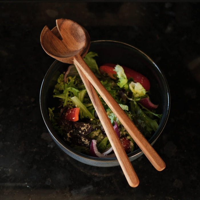 Keepsake Luca Salad Servers - A set of wooden salad servers rests on a bowl filled with mixed greens and vegetables.
