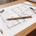Staedtler Graphite Pencil 175mm Round Barrel - A round barrel graphite pencil in natural wood colour resting on a blueprint of a house layout on a wooden table.
