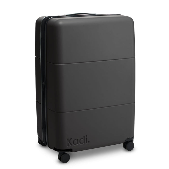Kadi Check-In Suitcase - Large - A large black suitcase with a smooth exterior and wheels, featuring a brand logo on the side.