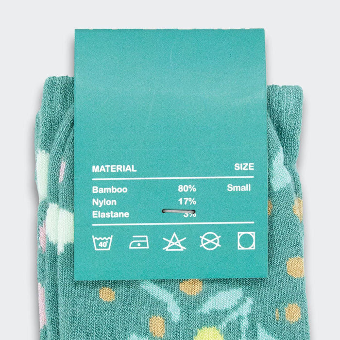 Jolly Knitted Bamboo Kids Socks - A pair of teal kids’ socks featuring a floral design with coloured dots, attached to a material and size label.