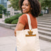 Custom Felt Logo Hanging Tag - A woman with curly hair smiles while carrying a cream-coloured tote bag with a logo.
