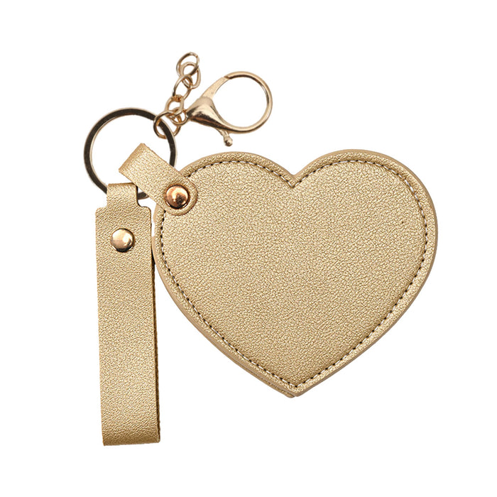 Heart-Shaped Compact Mirror with Keychain - A heart-shaped compact mirror with a keychain, featuring a gold textured finish and a gold clasp.