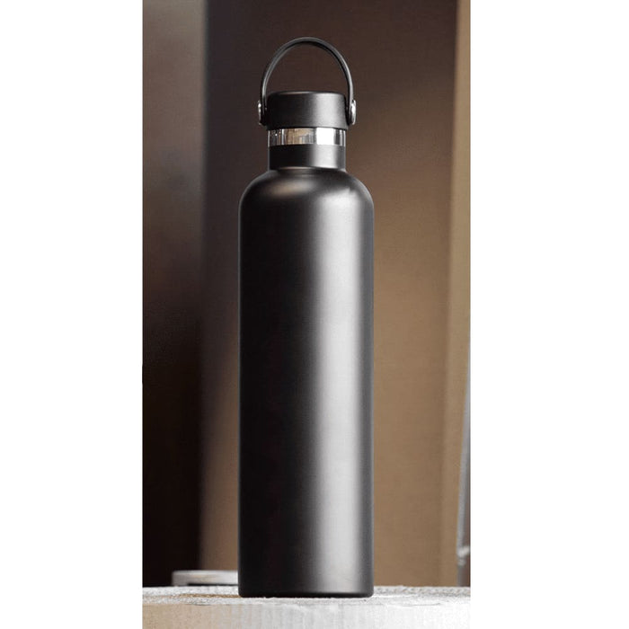 The Tank 2.0 Stainless Steel 1L Drink Bottle - A drink bottle made of stainless steel, featuring a matte black finish and a carrying handle. It has a logo on the side.