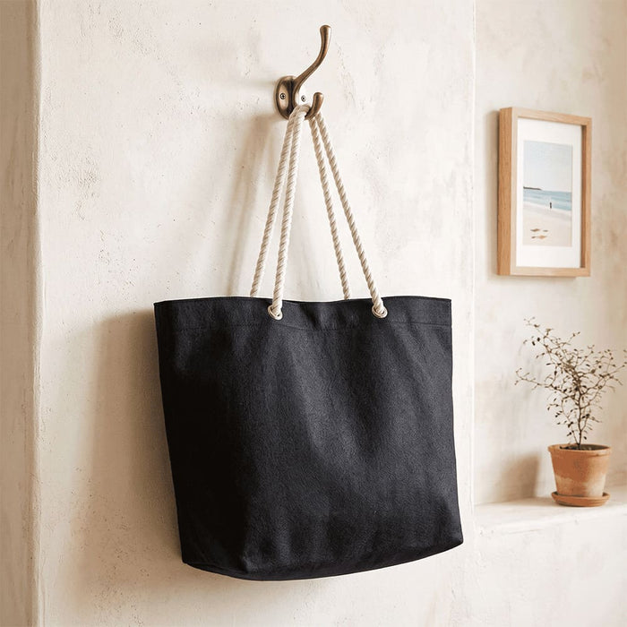Florida GRS Recycled Beach Tote Bag - A black recycled beach tote bag with rope handles hangs on a hook against a textured wall.