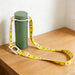 2 in 1 Water Bottle Lanyard - A drink bottle in green with a white lanyard featuring a yellow design and animal motifs.