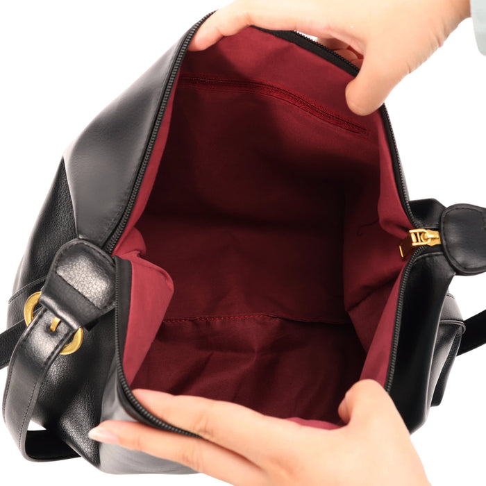 Dumpling Polyurethane Tote Bag - A black tote bag opened to reveal a burgundy lining, held by a pair of hands. The bag features a gold zip closure.