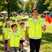 Hi-Vis Reflective Trim Velcro Placket Safety Vest - A group of children and an adult wearing bright yellow Hi-Vis reflective vests, walking in a park.
