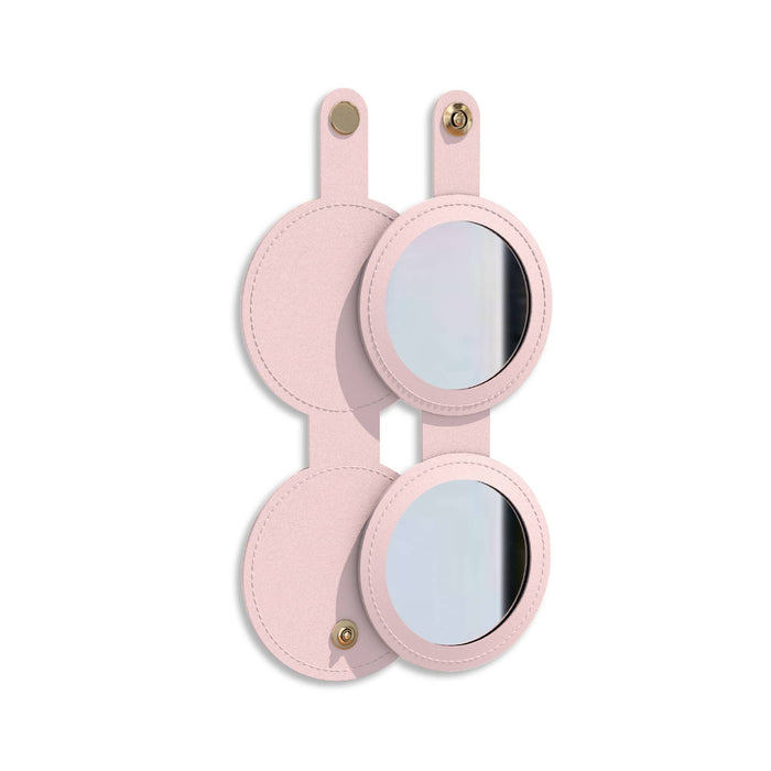 Round Folding Pocket Mirror - A round folding pocket mirror in a soft pink casing, featuring a logo on the front and two mirrored surfaces.