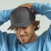 Sonic-S Organic/Recycled Trucker - A grey trucker cap with a mesh back, worn by a smiling man in a light blue sweatshirt.