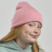 Kid Wind-S Beanie - Recycled Polyester - A pink ribbed beanie worn by a girl with red hair and freckles, featuring a logo on the side.