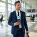MiTag Duo Passport Holder with Global Tracking Tag - A man in a navy suit holds a passport in an airport terminal with large windows and people in the background.